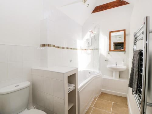 a white bathroom with a toilet and a sink at Tump Cottage in Nympsfield