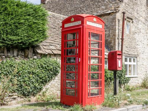 an old red phone booth in front of a house at Tump Cottage in Nympsfield