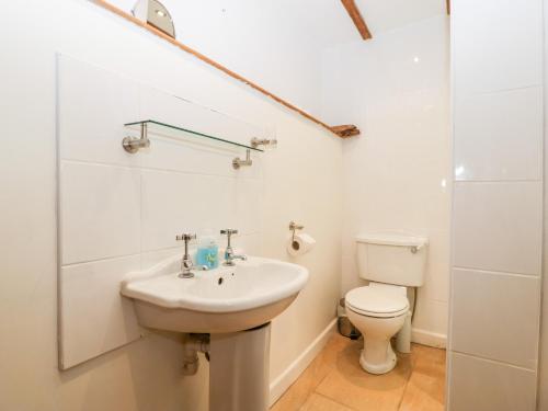 a white bathroom with a sink and a toilet at Nympy Cottage in Nympsfield