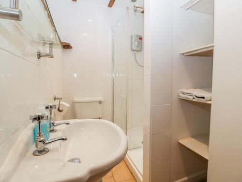 a white bathroom with a sink and a shower at Nympy Cottage in Nympsfield