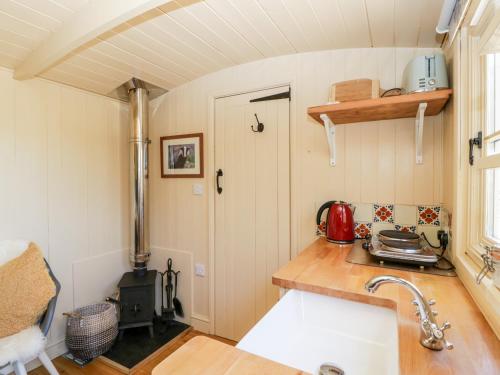 una piccola cucina con piano cottura e lavandino di The Hut a Nymphsfield