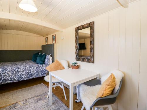 una camera con tavolo, specchio e letto di The Hut a Nymphsfield