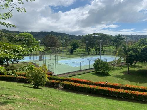 a tennis court in a park with flowers at Stay In CR Los Sueños Condos in Jacó
