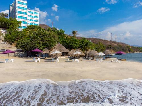a beach with chairs and umbrellas and the ocean at Hotel Santorini Casablanca in Santa Marta