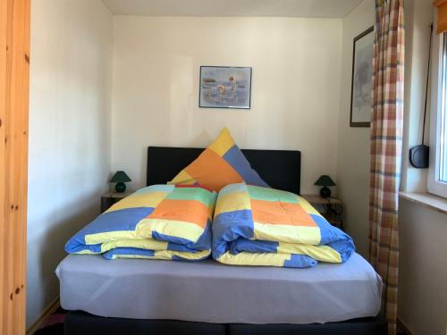una cama con almohadas coloridas en una habitación en Ferienhaus auf Usedom, Neeberg, en Krummin