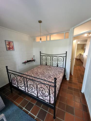 a bedroom with a black bed in a room at Gezellig appartement in groene omgeving in Drijhoeven
