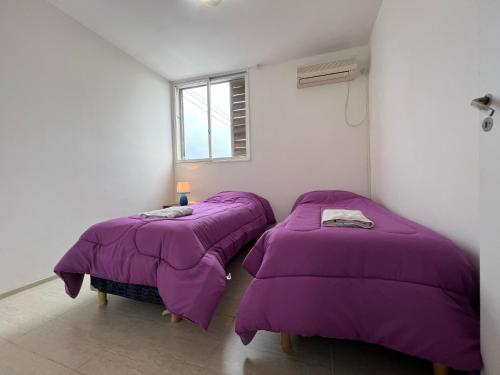 2 camas en una habitación con mantas moradas en Apartamento Lela en Mendoza