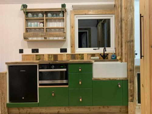 a kitchen with green cabinets and a sink at Rusty - Shepherds hut sleeps up to 4 in Sidlesham