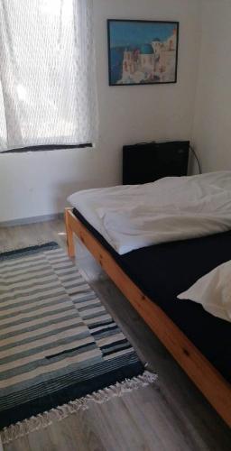 a bedroom with a bed and a rug and a window at Szentendrei sziget, modern faház, télen is in Szigetmonostor