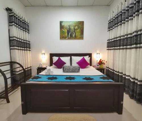 a bedroom with a large bed with purple pillows at Levona Garden Resort in Habarana