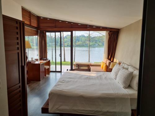 um quarto com uma cama e vista para a água em Flamingo Đại Lải Resort - Lake view villa em Phúc Yên