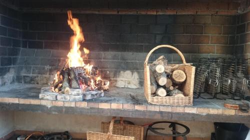a brick fireplace with a basket of logs and a fire at Ciudad Encantada Tio Daniel in Valdecabras