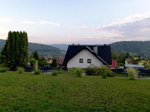 a white house with a black roof in a field at Domki Na Stoku Laworty in Ustrzyki Dolne