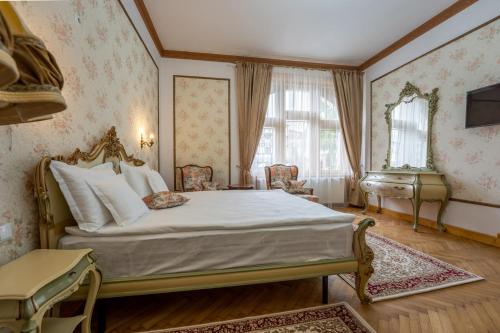 um quarto com uma cama, uma cadeira e uma janela em Clasic Haus Sighisoara em Sighisoara