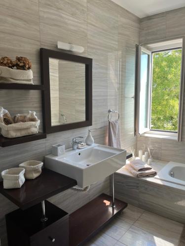 La salle de bains est pourvue d'un grand lavabo blanc et d'une baignoire. dans l'établissement la PADINI CASA sul mare, à Néoi Epivátai