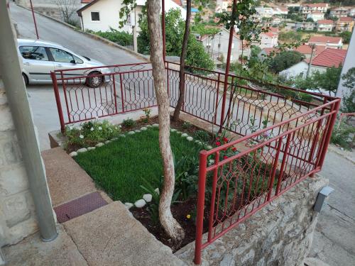 a red fence next to a tree next to a street at Studio apartman Jakšić in Trebinje
