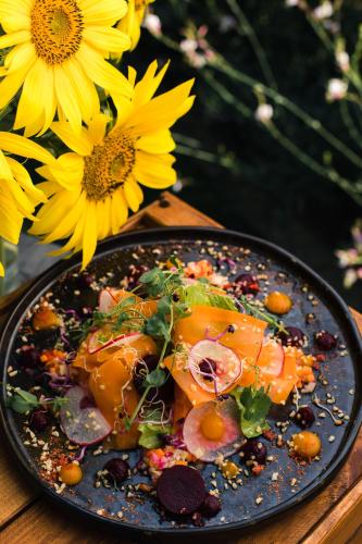 a plate of food on a table next to flowers at Tópart Hotel in Balatonvilágos