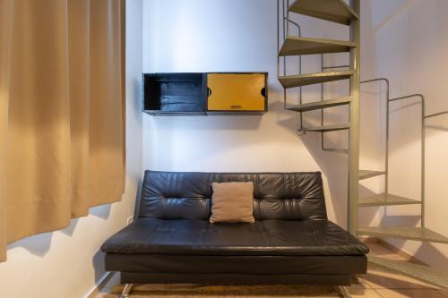 a black leather couch in a room with a staircase at BH Studios Hotel Brás in Sao Paulo