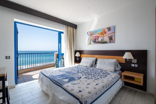 a bedroom with a bed with a view of the ocean at Apartamentos Playa Feliz in Playa del Ingles