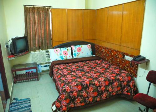 a bedroom with a bed and a tv at Hotel New West Tower in Madurai