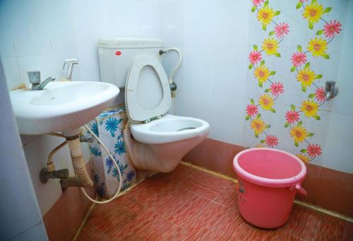 ein Badezimmer mit einem WC, einem Waschbecken und einem Eimer in der Unterkunft Hotel New West Tower in Madurai