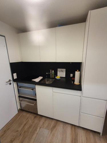 a kitchen with white cabinets and a black counter top at Phoenix Studio - Haus Astral - Zermatt in Zermatt