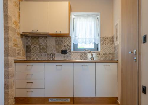 a kitchen with white cabinets and a window at Sirius luxury Boutique in Sivota