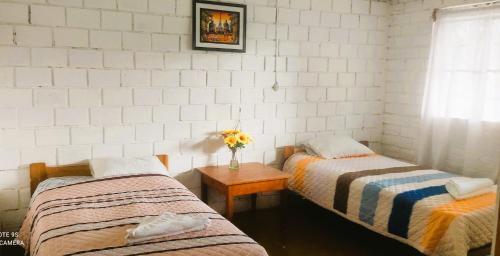 a room with two beds and a table with a vase of flowers at Selva Mayo in Moyobamba
