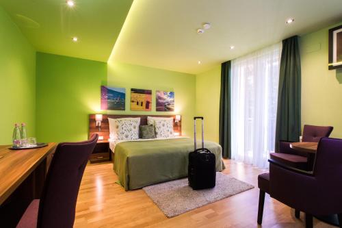 Tópart Hotel في بالاتونفيلاجوس: غرفة نوم مع سرير ومكتب وطاولة مع حقيبة