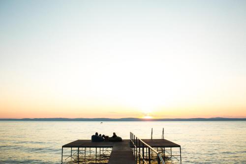 a group of people sitting on a dock in the water at Tópart Hotel in Balatonvilágos