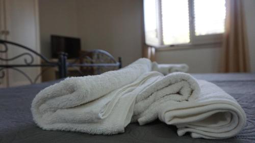 una pila de toallas blancas sentadas en una cama en Country house relais Nonna Rosa Rosolini (SR) en Siracusa