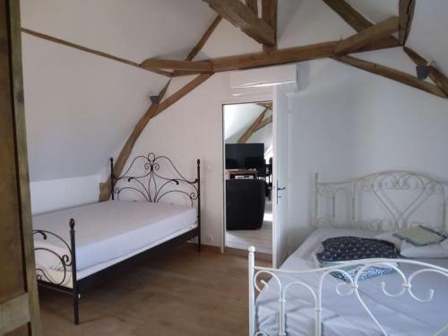 une chambre avec deux lits et un miroir dans l'établissement Le Manoir, à Chanceaux-sur-Choisille