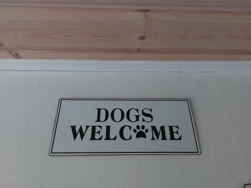 a sign that says dogs welcome me on a wall at KRAGKAER Deer-Lodge B&B & Guest House - Unique Holiday Homes in Sæby
