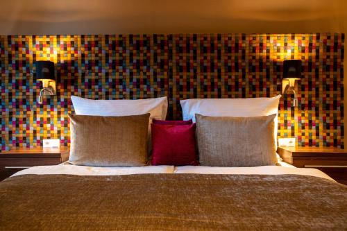 a bedroom with a bed with pillows and a wall at Tópart Hotel in Balatonvilágos