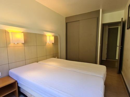 - une chambre avec un lit blanc et des lumières sur le mur dans l'établissement 2 pièces confort · 5 pers · Proche pistes et commerces · WIFI · Non fumeur · Casier à ski - FR-1-425-165, à Flaine