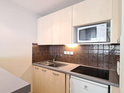 une cuisine avec un évier et un micro-ondes dans l'établissement Appartement confortable Proche des pistes Casier à ski - FR-1-425-153, à Flaine