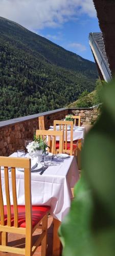 a table with white table cloth and wooden chairs with a view at Hotel Ransol in El Tarter