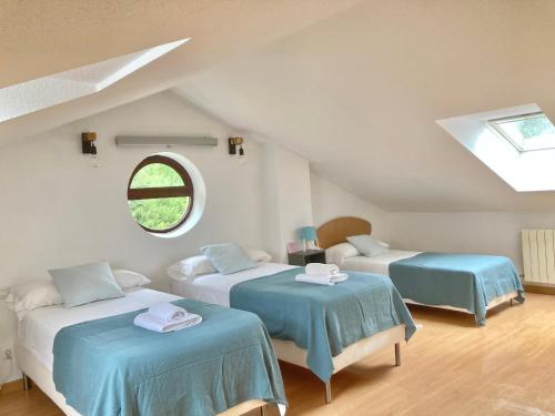 um quarto no sótão com 2 camas e uma janela em Somo Surfskate hostel em Castanedo