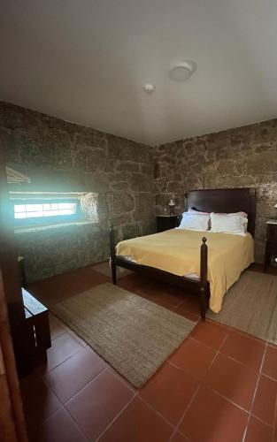 a bedroom with a bed and a stone wall at Agro-Turismo - Quinta do Pinheiro in Cavadoude