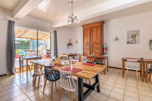 a dining room with a wooden table and chairs at Hotel Les Vieux Acacias in Queyrac