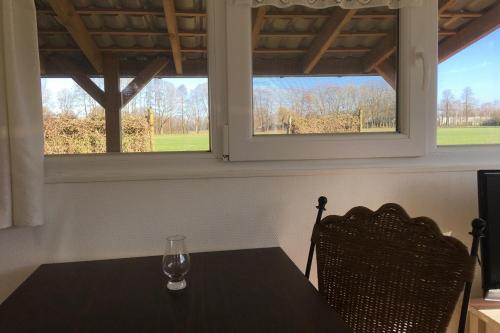 een tafel en twee stoelen in een kamer met twee ramen bij Chalet Op de Brusse in De Heurne