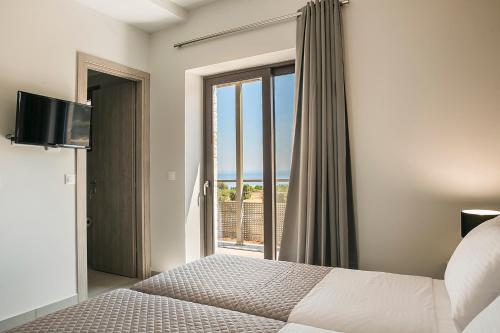a bedroom with a bed and a large window at Petradi Villas Skala in Skala Kefalonias