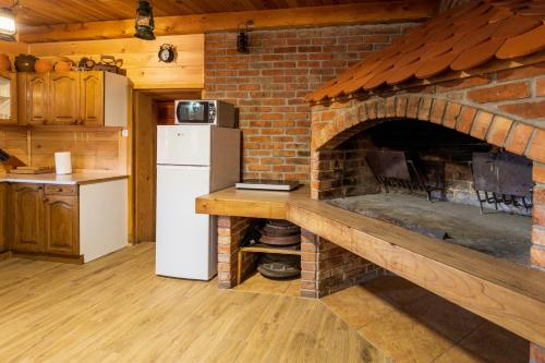 a kitchen with a brick oven with a white refrigerator at Kuća za odmor Lara in Otočac