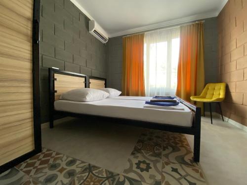 a bedroom with a bed and a yellow chair at Valentina Guest House in Tsandrypsh