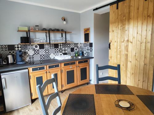 a kitchen with wooden cabinets and a table and chairs at Gîte équestre. Ferme des Essarts in Maucomble