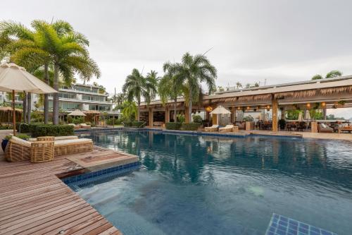 una gran piscina con sillas y sombrillas en un complejo en Selina Serenity Rawai Phuket, en Rawai Beach