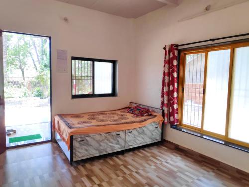 a bedroom with a bed in a room with windows at Ashish Baug Cottage in Alibaug