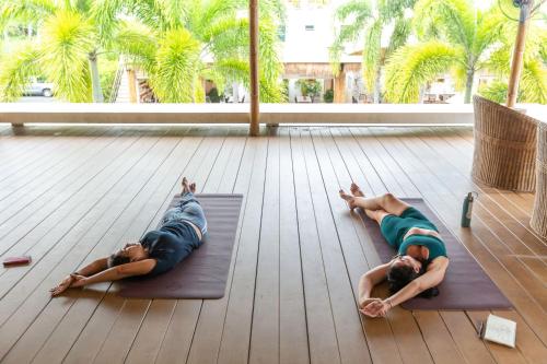two people laying on mats on the floor in a building at Selina Serenity Rawai Phuket in Rawai Beach