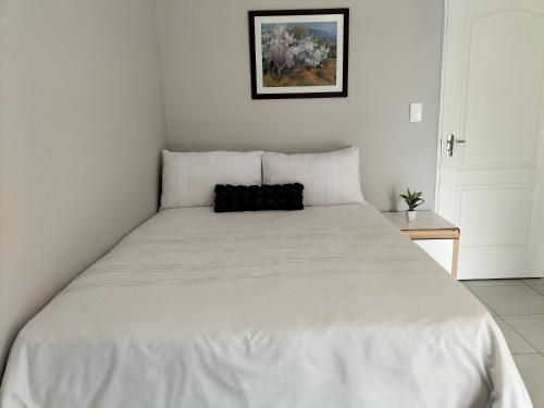 um quarto com uma cama branca e uma almofada preta em The Terrace Guest House em Roodepoort