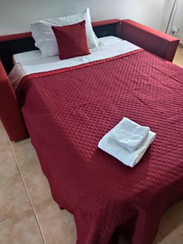 a bed with red sheets and white towels on it at Oro&Mattia's House in Trapani